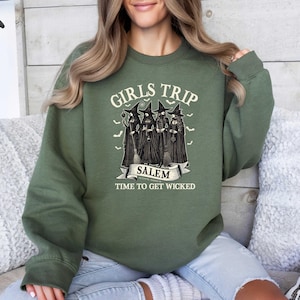 May include: Green sweatshirt with the text "Girls Trip Salem Time to Get Wicked" and a graphic of four witches with broomsticks.