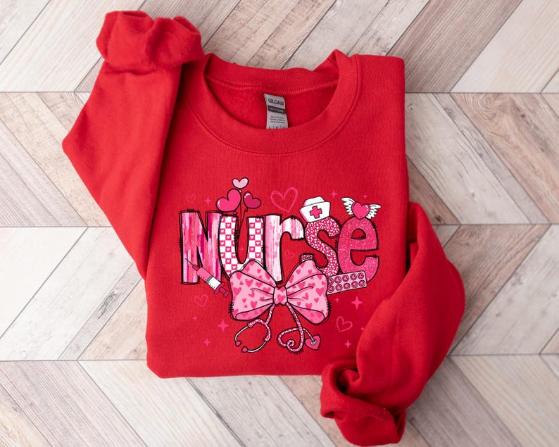 Peut inclure: Sweat-shirt rouge avec un motif rose et blanc qui dit "Infirmi&egrave;re" avec des c&oelig;urs et d'autres symboles m&eacute;dicaux.