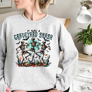 May include: Gray sweatshirt with a graphic of three skeletons dancing with the text "It was a Graveyard Smash" printed on the front.