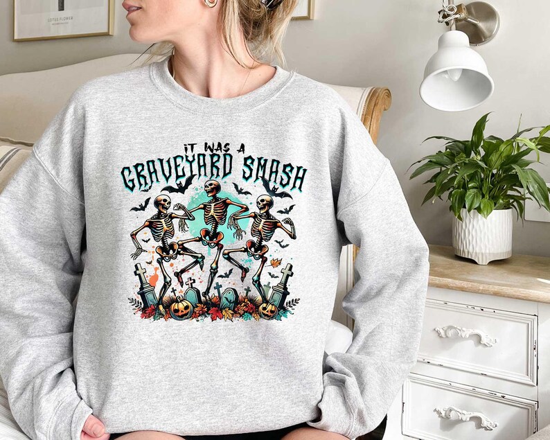 May include: Gray sweatshirt with a graphic of three skeletons dancing with the text "It was a Graveyard Smash" printed on the front.