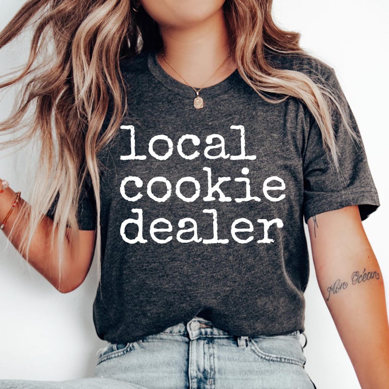 May include: A dark gray t-shirt with the text "local cookie dealer" printed in white.