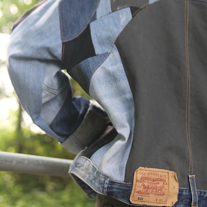 K&ouml;nnte beinhalten: Eine Jeansjacke aus Patchwork-Jeansstoff. Die Jacke hat ein braunes Lederlabel mit dem Text "Levi Strauss & Co. Original riveted quality clothing XX" und der Nummer "501" darauf gedruckt.