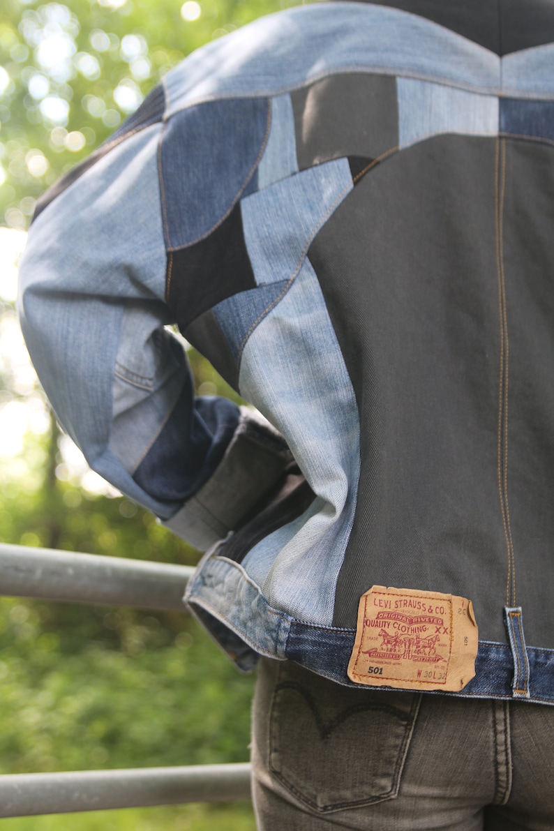 K&ouml;nnte beinhalten: Eine Jeansjacke aus Patchwork-Jeansstoff. Die Jacke hat ein braunes Lederlabel mit dem Text "Levi Strauss & Co. Original riveted quality clothing XX" und der Nummer "501" darauf gedruckt.