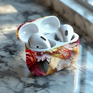 May include: White wireless earbuds in a floral patterned case. The case is open, revealing the earbuds and the interior. The case features a design of red, pink, yellow, and white flowers and leaves.