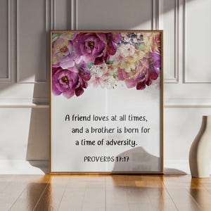Peut inclure: Une affiche encadrée avec un arrangement floral de fleurs roses et violettes. Le texte "A friend loves at all times, and a brother is born for a time of adversity. PROVERBS 17:17." est affiché.