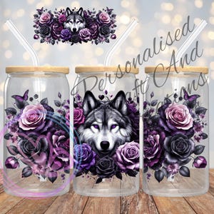 May include: Three glass tumblers with wooden lids and clear straws. Each tumbler features a wolf's head surrounded by purple and black roses and other floral elements.