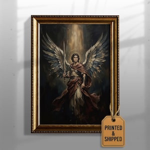 Peut inclure: Une impression d'art encadrée représentant une figure ailée tenant une épée, éclairée par un faisceau de lumière vertical sur un fond sombre. La figure porte une cape rouge sur des vêtements clairs. Une étiquette beige attachée au cadre indique PRINTED & SHIPPED.