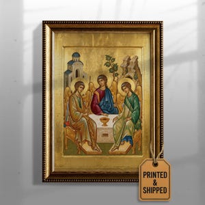 May include: Framed religious icon featuring three figures in robes seated around a table. The artwork has gold leaf background and a decorative gold frame. The image includes the text "PRINTED & SHIPPED" on a tag.