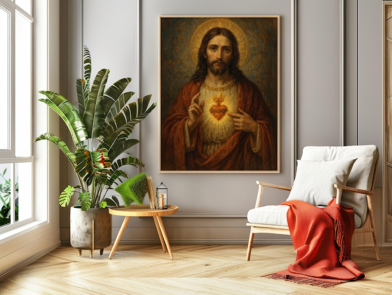 May include: A framed religious artwork depicting Jesus Christ with a golden halo and a glowing heart. The painting is in a room with a plant, a small table, a chair, and an orange throw blanket.
