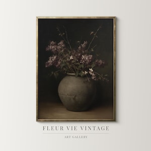 May include: A framed vintage art print featuring a still life of purple lilacs in a gray ceramic vase. The artwork has a dark, moody aesthetic with the text "FLEUR VIE VINTAGE" and "ART GALLERY" at the bottom.