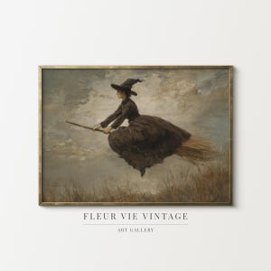 Könnte beinhalten: Gerahmter Vintage-Kunstdruck mit einer Hexe in dunklem Kleid und Hut, die auf einem Besen fliegt. Das Kunstwerk hat eine gedämpfte Farbpalette mit einem bewölkten Himmel im Hintergrund und dem Text "FLEUR VIE VINTAGE ART GALLERY".
