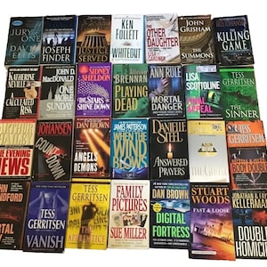 May include: A collection of hardcover books with various titles and authors, including "Angels & Demons" and "Digital Fortress." The books feature colorful covers with text and images, suggesting a mystery or thriller genre.