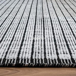 May include: A black and white striped rug with a textured surface. The rug features vertical black stripes against a white background. The rug is made of a soft material and is suitable for a living room or bedroom.