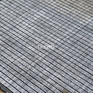 May include: A rectangular rug with a striped pattern. The rug features alternating black and off-white stripes running diagonally across the surface. The rug is made of a woven material and has a dark border.