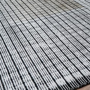 May include: A black and white striped rug with a textured surface. The rug features vertical stripes, creating a pattern across the surface. The rug is made of a woven material.