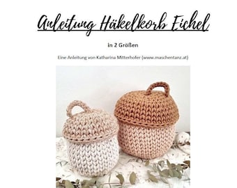 May include: Two crocheted acorn-shaped baskets, one brown and one beige, with a handle on top. The baskets are sitting on a white and green floral fabric.