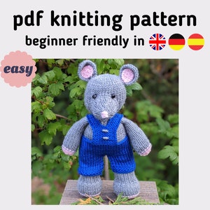 May include: Knitting pattern for a grey mouse wearing blue dungarees. The pattern is labelled "easy" and is available in English, German, and Spanish.