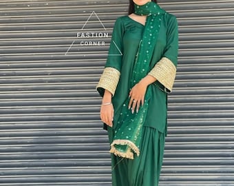 Könnte beinhalten: Ein grünes Salwar-Kameez-Outfit mit passendem Schal. Das langärmlige Oberteil hat goldgestickte Manschetten. Das Outfit wird mit einer passenden Hose getragen. Der Text "FASHION CORNER" ist im Bild sichtbar.