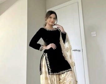 May include: Black velvet salwar kameez with gold embroidery on the neckline and side seams. The outfit includes a cream-colored, patterned salwar and a matching dupatta. The traditional Indian ensemble is elegant and suitable for special occasions.