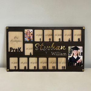 May include: A dark brown wooden school years photo display with spaces for photos from Pre-K to 12th grade. The name "Stephan William" is in gold lettering. Includes a photo of a graduate.