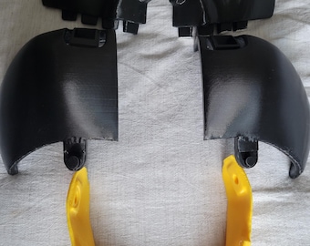 May include: A set of black plastic 3D printed parts for a costume, including two skull-shaped pieces, two dome-shaped pieces, and a yellow plastic piece shaped like a U.