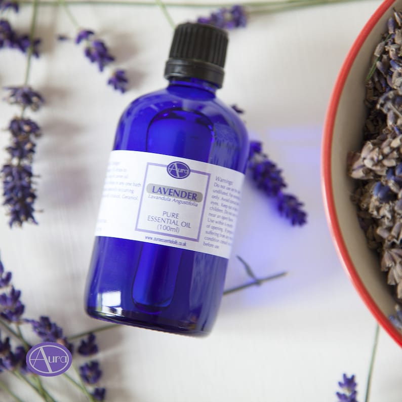 May include: A blue glass bottle of lavender essential oil with a white label that reads "Lavender Lavandula Angustifolia Pure Essential Oil (100ml) www.auramed.co.uk".