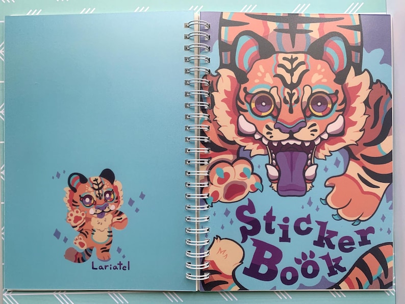 May include: A blue spiral bound sticker book with a colorful tiger illustration on the cover. The cover text reads "Sticker Book".