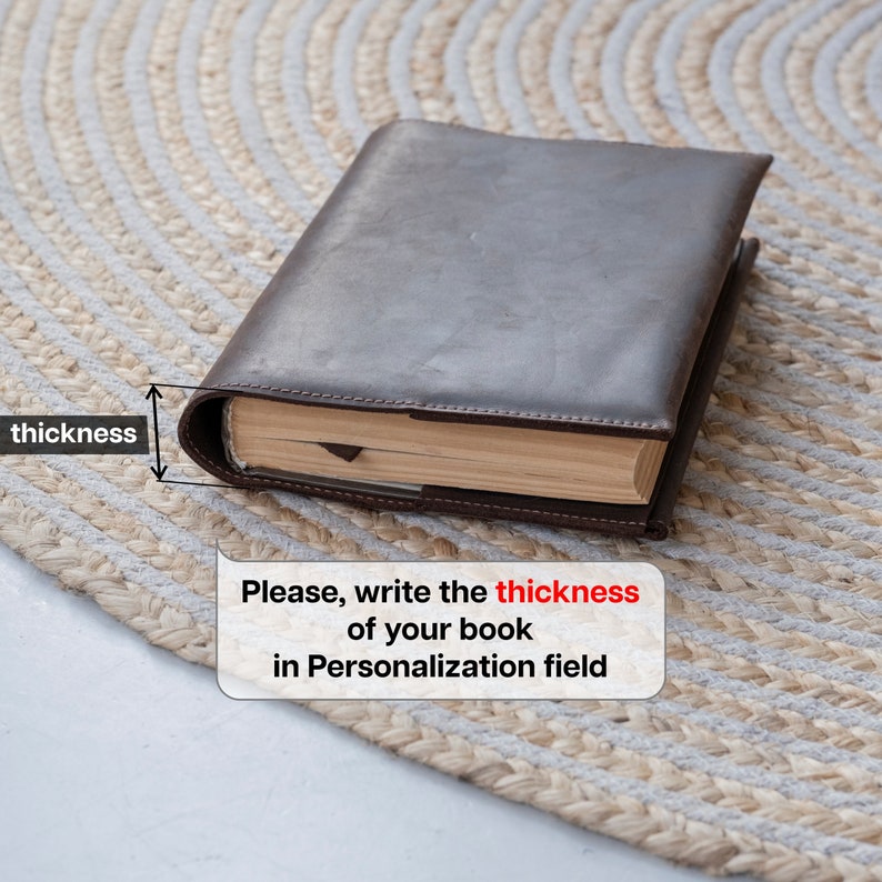 May include: A dark brown leather book cover enclosing a book with beige pages. A graphic overlay indicates the thickness of the book with an arrow and the text "thickness". A speech bubble contains the text "Please, write the thickness of your book in Personalization field".