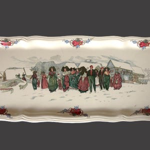 May include: A white ceramic serving tray with a winter scene featuring a group of people in colorful clothing. The tray has a scalloped edge and is decorated with floral designs.