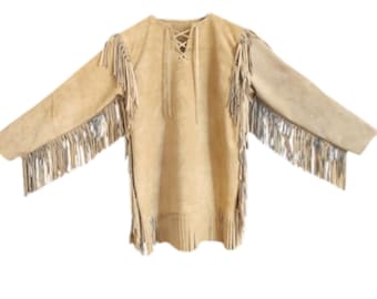 May include: A tan suede tunic with long sleeves and fringe detailing. The tunic features a lace-up neckline and fringe along the sleeves and hem. The garment is made of a soft, light-colored suede material.