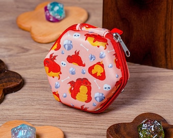 Könnte beinhalten: Eine sechseckige Würfeltasche in Pink und Rot mit Reißverschluss. Die Tasche ist mit einem sich wiederholenden Muster aus kleinen roten Drachen und weißen Knochen auf rosa Hintergrund verziert.
