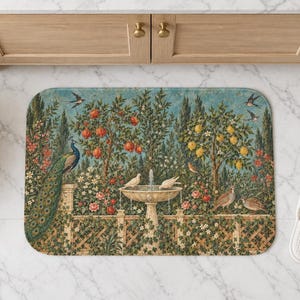 Può includere: Un tappetino da bagno rettangolare con una dettagliata scena di giardino che presenta una fontana in pietra centrale, un pavone sulla sinistra, vari uccelli, alberi di melograno e limoni e piante rampicanti su un cielo azzurro.