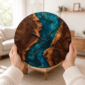 Puede incluir: Un reloj de pared circular con un borde de veta de madera natural y una incrustación central de resina azul y turquesa. La esfera del reloj tiene finas marcas de hora doradas y dos manecillas negras centradas en la sección de resina.
