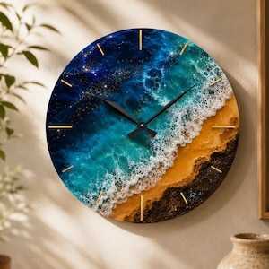 Puede incluir: Un reloj de pared redondo que presenta una vibrante escena oceánica con agua azul profundo, olas turquesas, espuma de mar blanca y una playa de arena. La esfera tiene finas marcas horarias doradas y manecillas negras sobre una superficie circular.