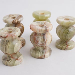 May include: Five green and brown marble candle holders with a round base and a cylindrical top. The candle holders are made of natural stone and have a unique, swirling pattern.