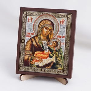 May include: A wooden icon of the Virgin Mary and baby Jesus. The icon is painted in a traditional style with gold accents. The Virgin Mary is holding the baby Jesus in her arms and looking down at him. The icon is framed in a dark wood frame.