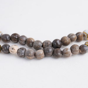 May include: A brown and white beaded necklace with gold accents. The beads are made from natural materials and have a rustic look.