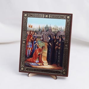 May include: A framed religious icon depicting a scene from the life of Saint Sergius of Radonezh. The icon features a group of people, including a man kneeling before a monk. The icon is painted in a traditional style with vibrant colours and intricate details. The frame is made of wood and has a gold finish.