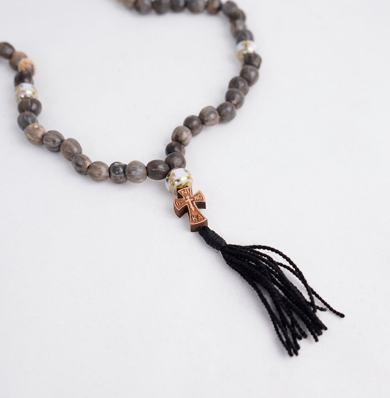 May include: A brown wooden rosary with a small wooden cross and a black tassel. The beads are made of natural wood and have a rustic look.