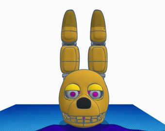 May include: A golden yellow animatronic head with large ears, a black nose, and pink eyes. The head is on a blue and purple background.