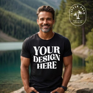 May include: A black t-shirt with the text "YOUR DESIGN HERE" in white. The shirt is being worn by a person standing in front of a lake and mountains.