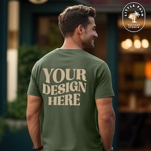 Puede incluir: Una camiseta verde con el texto "YOUR DESIGN HERE" impreso en la espalda.