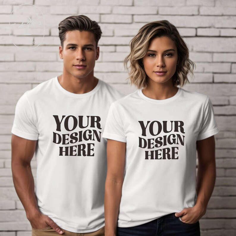 Peut inclure: Deux t-shirts blancs avec le texte "YOUR DESIGN HERE" en noir. Les chemises sont port&eacute;es par deux personnes.