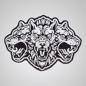 Puede incluir: Parche bordado en blanco y negro de un lobo de tres cabezas con una expresión de gruñido.