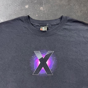 May include: A black short-sleeved t-shirt featuring a large, bold letter X centered on the chest. The X is layered over a vibrant, circular purple and pink nebula-like graphic with small white dots resembling stars. A Hanes brand tag is at the neck.
