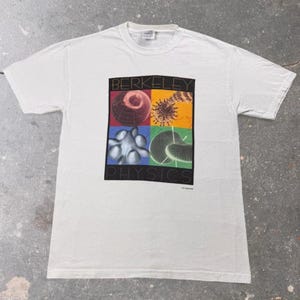 May include: A white short-sleeve t-shirt featuring a central graphic with the text BERKELEY PHYSICS. The design is divided into four colored quadrants containing scientific illustrations of a globe, a molecular structure, a fluid shape, and a grid.