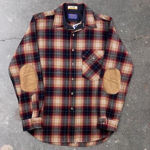 May include: A long-sleeve button-down shirt featuring a plaid pattern in shades of tan, red, black, and white. The shirt includes a single chest pocket, a dark collar, and tan suede-like elbow patches on both sleeves with visible brand labels.