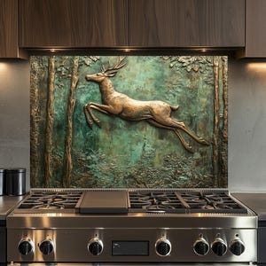 Puede incluir: Una estufa de acero inoxidable con una encimera negra y un protector contra salpicaduras con una escultura de ciervo de bronce en un entorno de bosque.