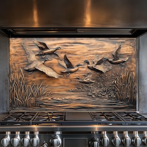 May include: A copper kitchen backsplash with a 3D embossed design of ducks flying over a pond. The backsplash is installed above a stainless steel stove with black burner grates.