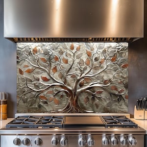 Puede incluir: Salpicadero de cocina metálico con diseño de árbol con hojas plateadas, cobrizas y bronce. El tronco y las ramas del árbol son de color bronce oscuro. El salpicadero está instalado sobre una cocina de gas de acero inoxidable.